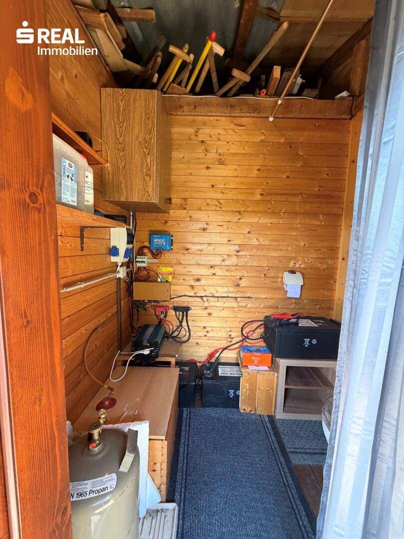 Technikraum mit Holzverkleidung, elektrischen Installationen, Batterien und Propangasflasche.