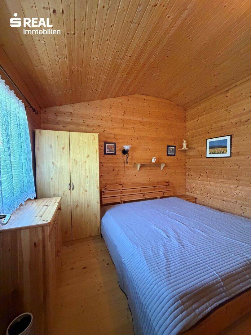 Gemütliches Schlafzimmer mit Holzverkleidung, Doppelbett und Fenster für natürliches Licht.
