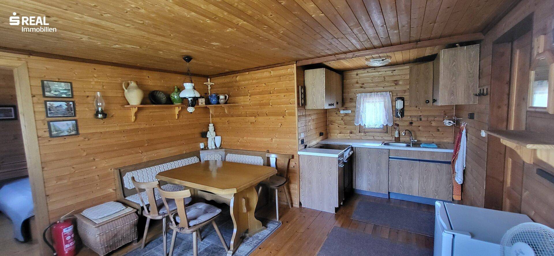 Gemütlicher Wohn-Essbereich mit Holztäfelung, rustikalen Möbeln und integrierter Küchenzeile.