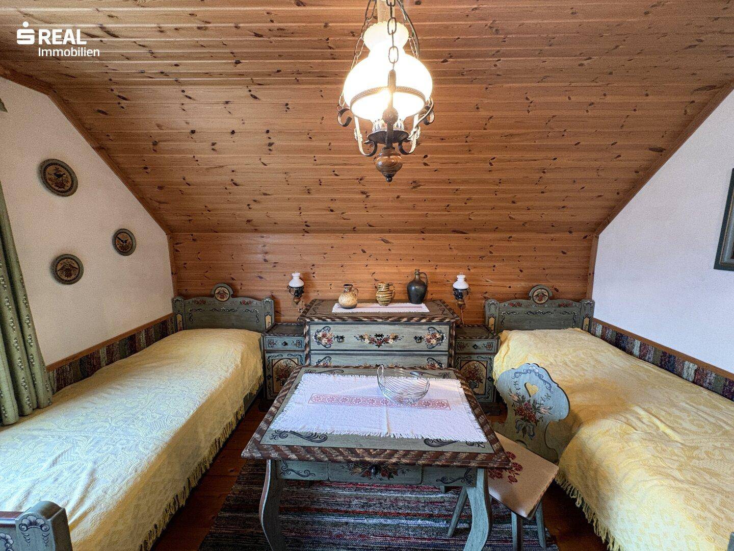 Traditionelles Schlafzimmer im Dachgeschoss mit zwei Einzelbetten und Holzbalkendecke.