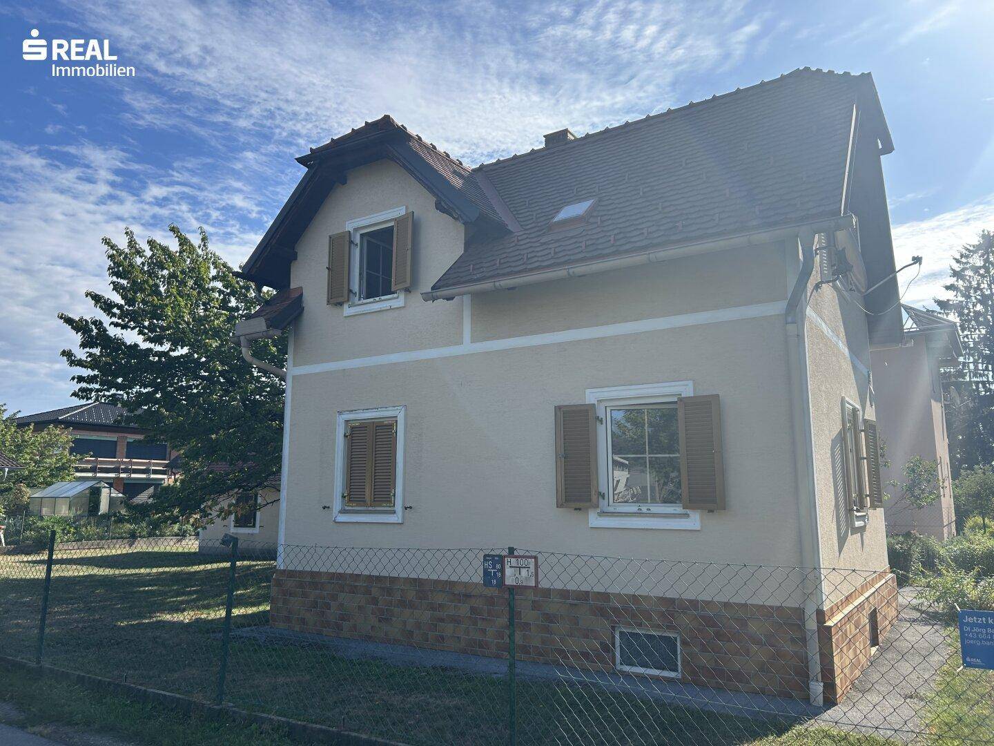 Weitere Außenansicht des Hauses mit Fenstern, Fensterläden und einem umzäunten Grundstück.