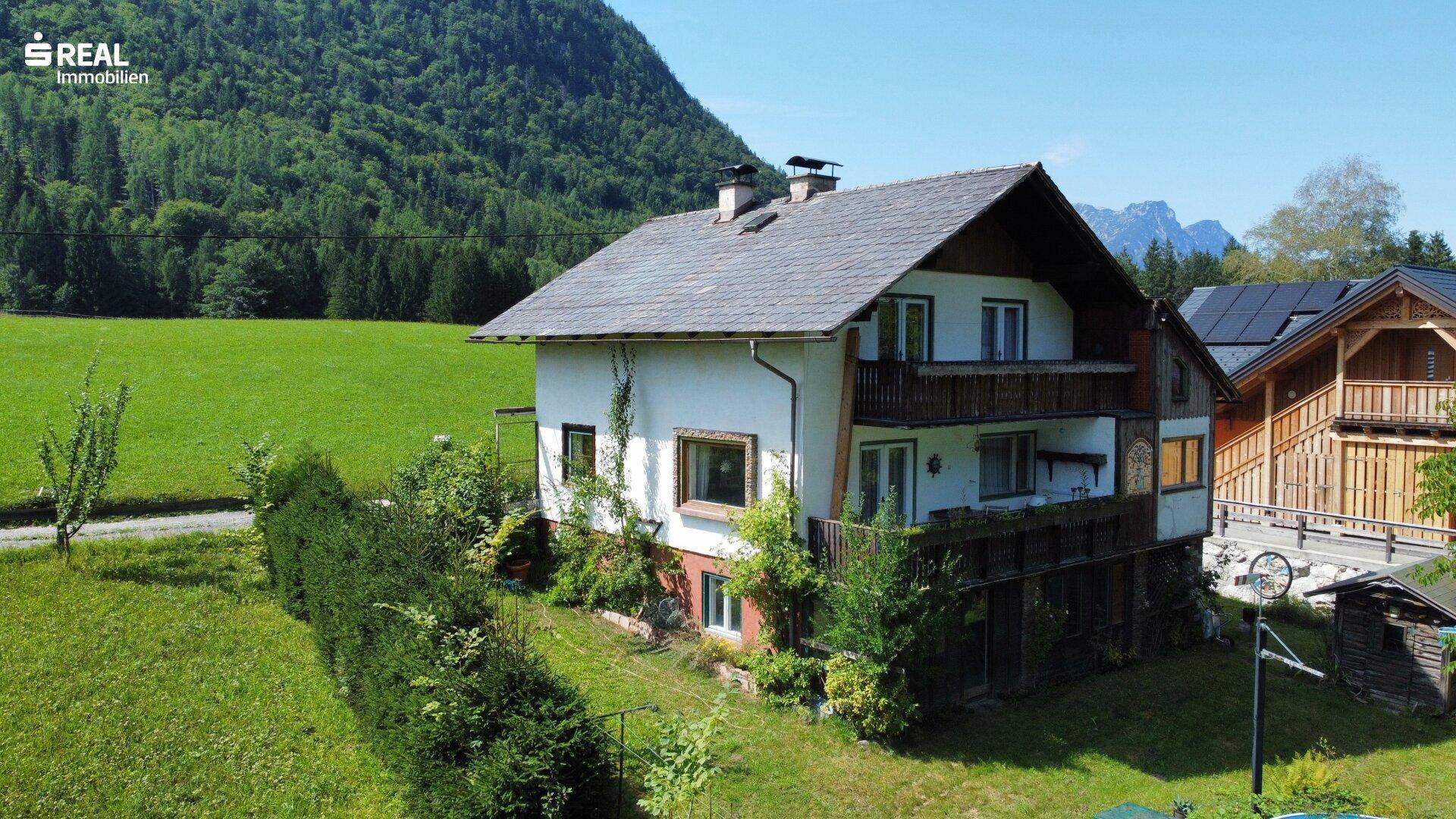 Charmantes Landhaus mit Satteldach und Balkonen, eingebettet in eine idyllische Berglandschaft.