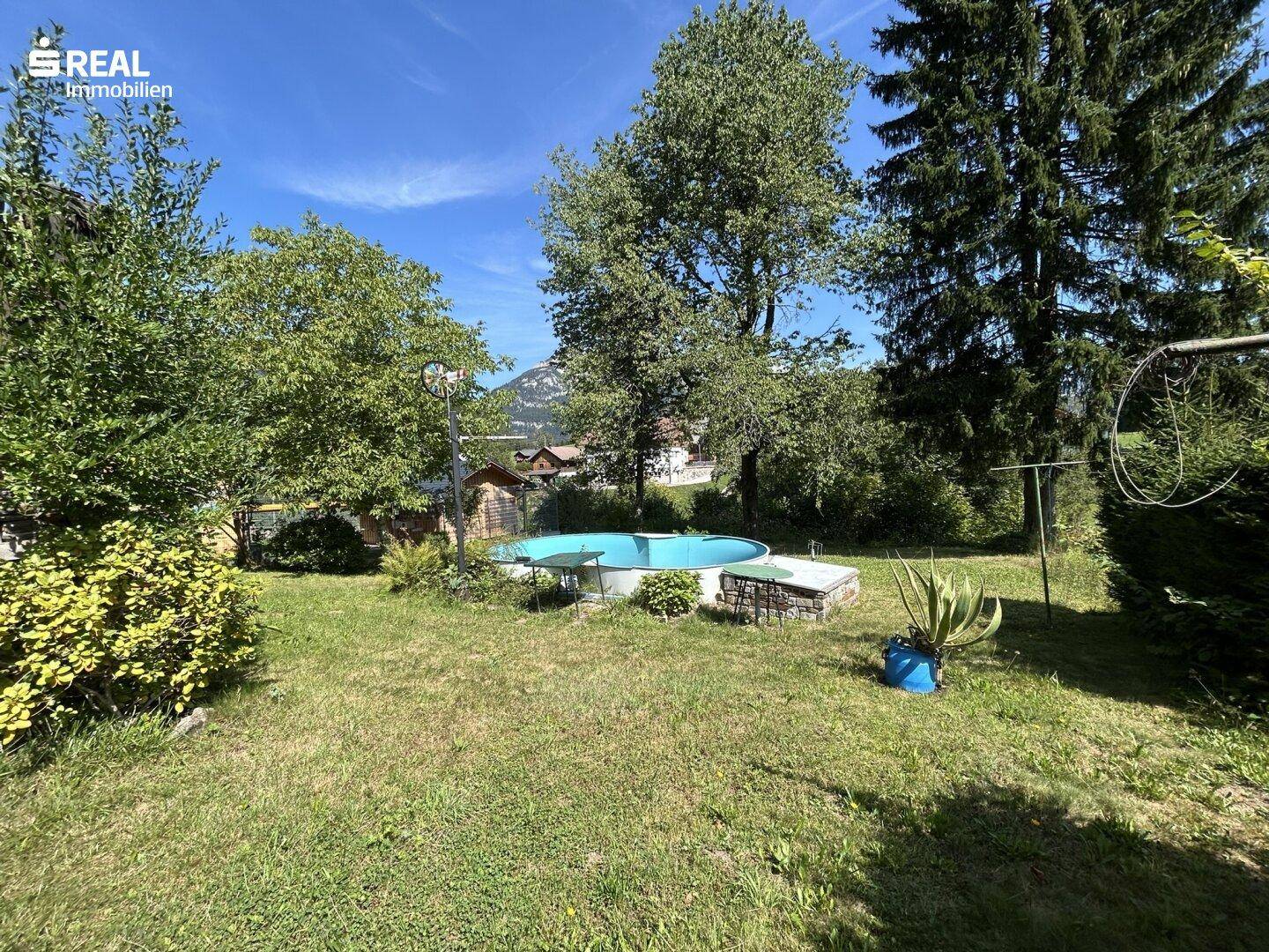 Großer Gartenbereich mit einem Aufstellpool, umgeben von Bäumen und grüner Natur.