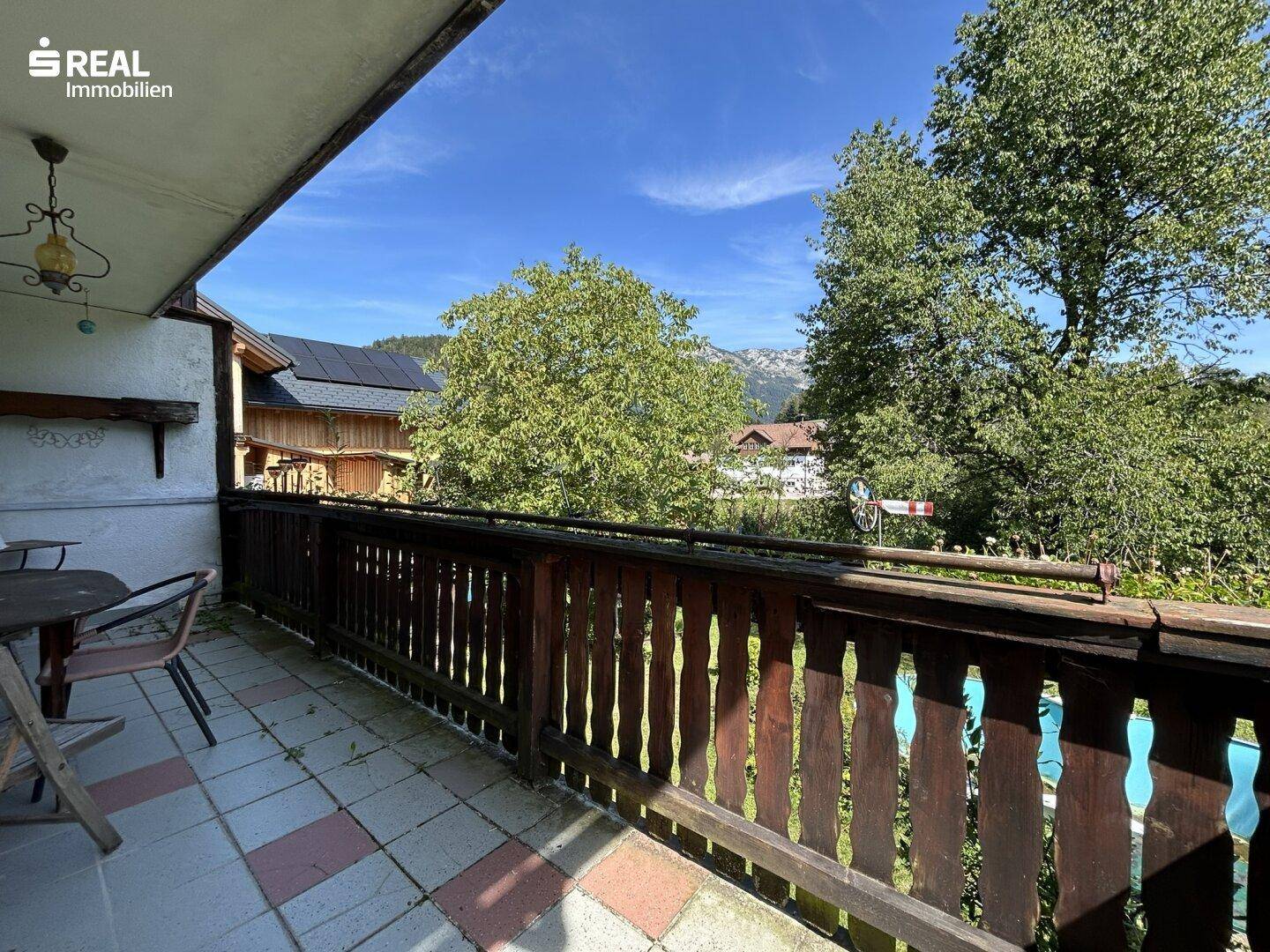 Balkon mit Holzbalkongeländer und gefliestem Boden, ideal für entspannte Stunden im Freien.
