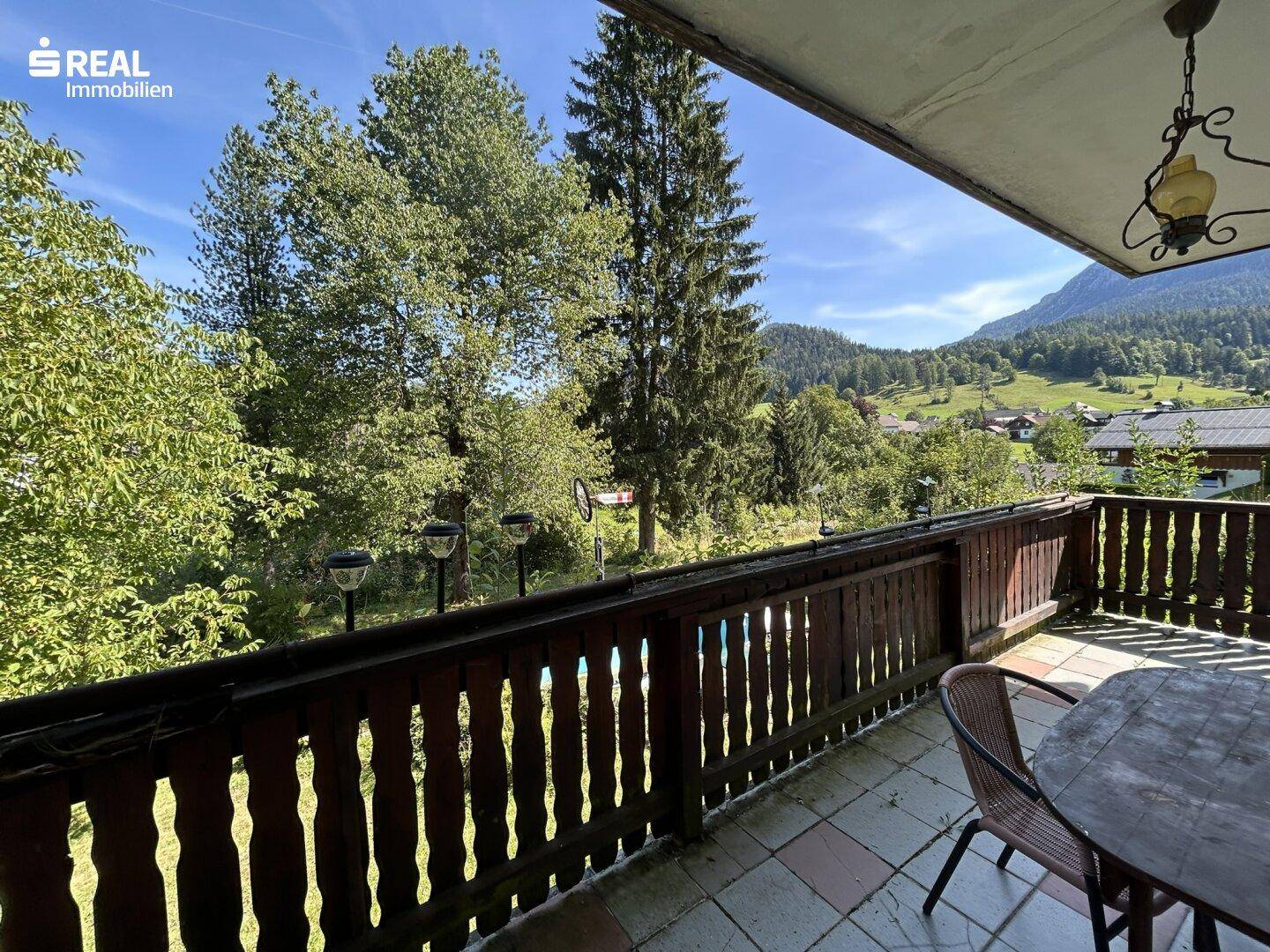 Geräumiger Balkon mit Sitzgelegenheiten und weitem Blick über die grüne Landschaft und Berge.