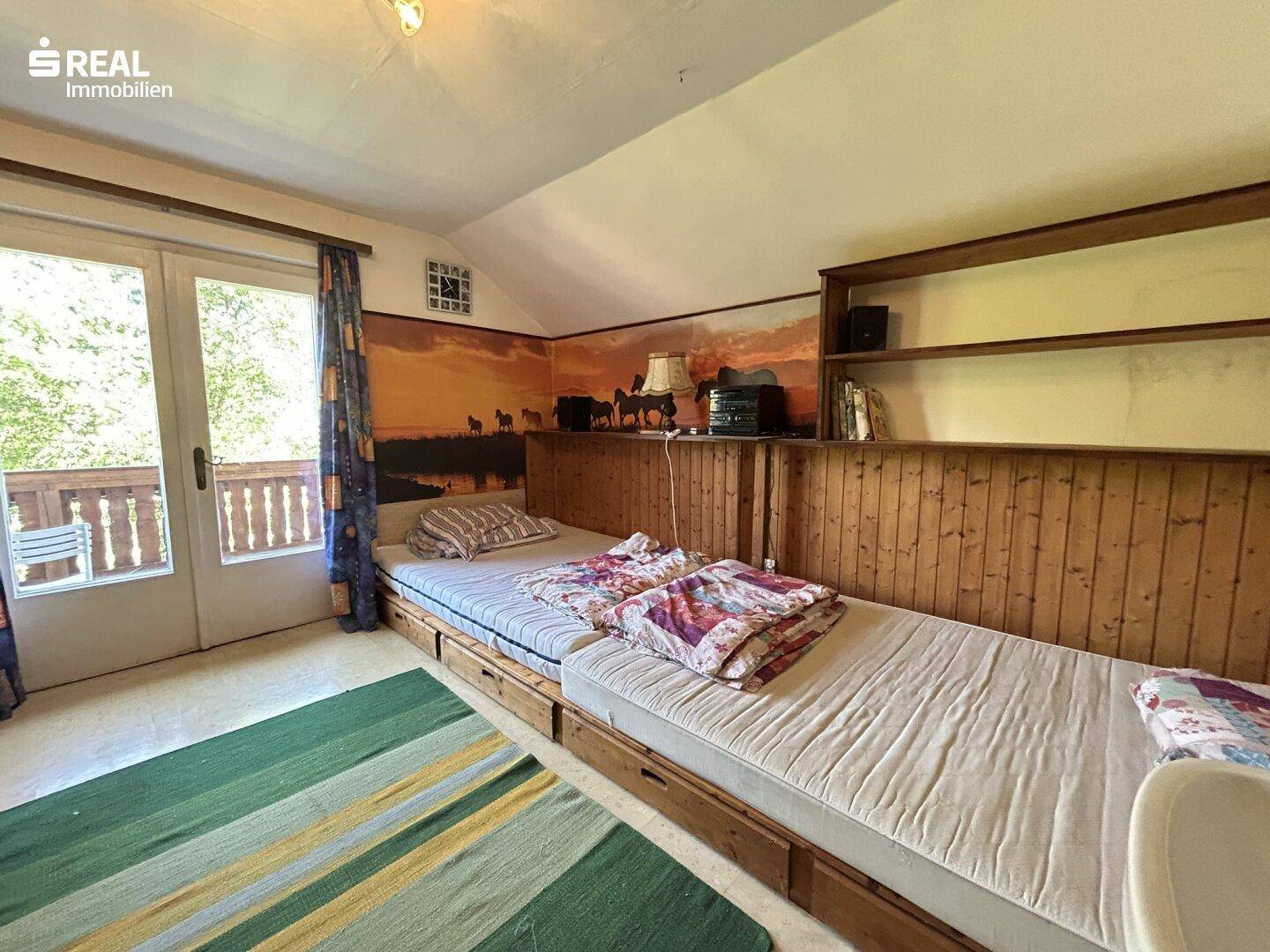 Schlafzimmer mit zwei Einzelbetten, Holzvertäfelung und direktem Zugang zum Balkon.