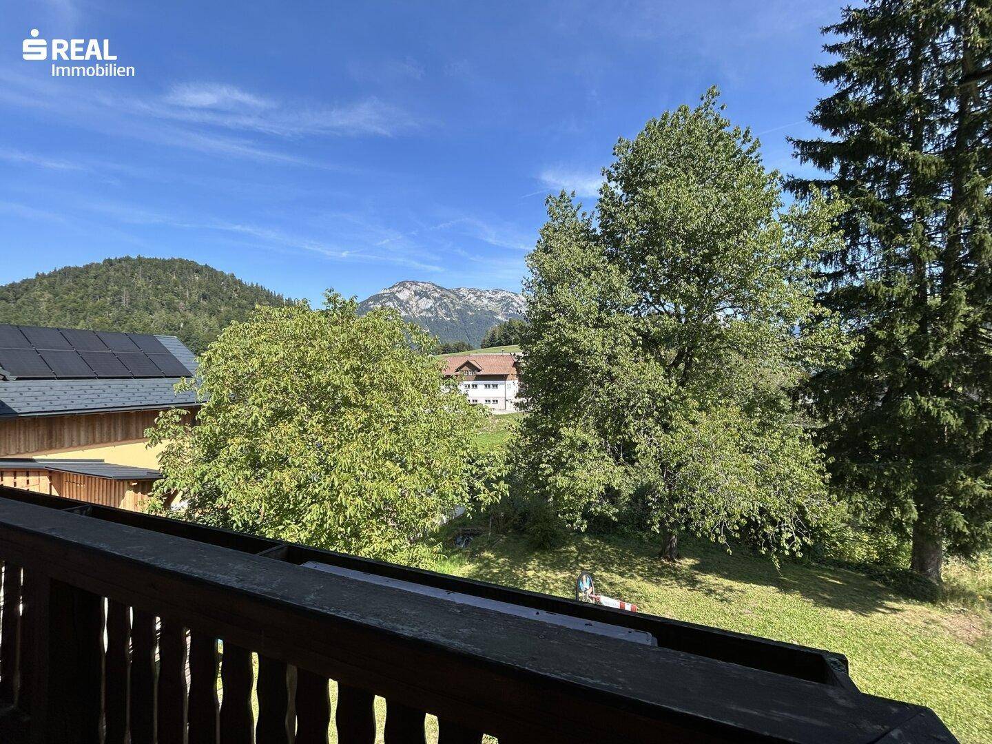 Balkon mit weitem Blick auf die Berge und ein benachbartes Haus mit Photovoltaikanlage.