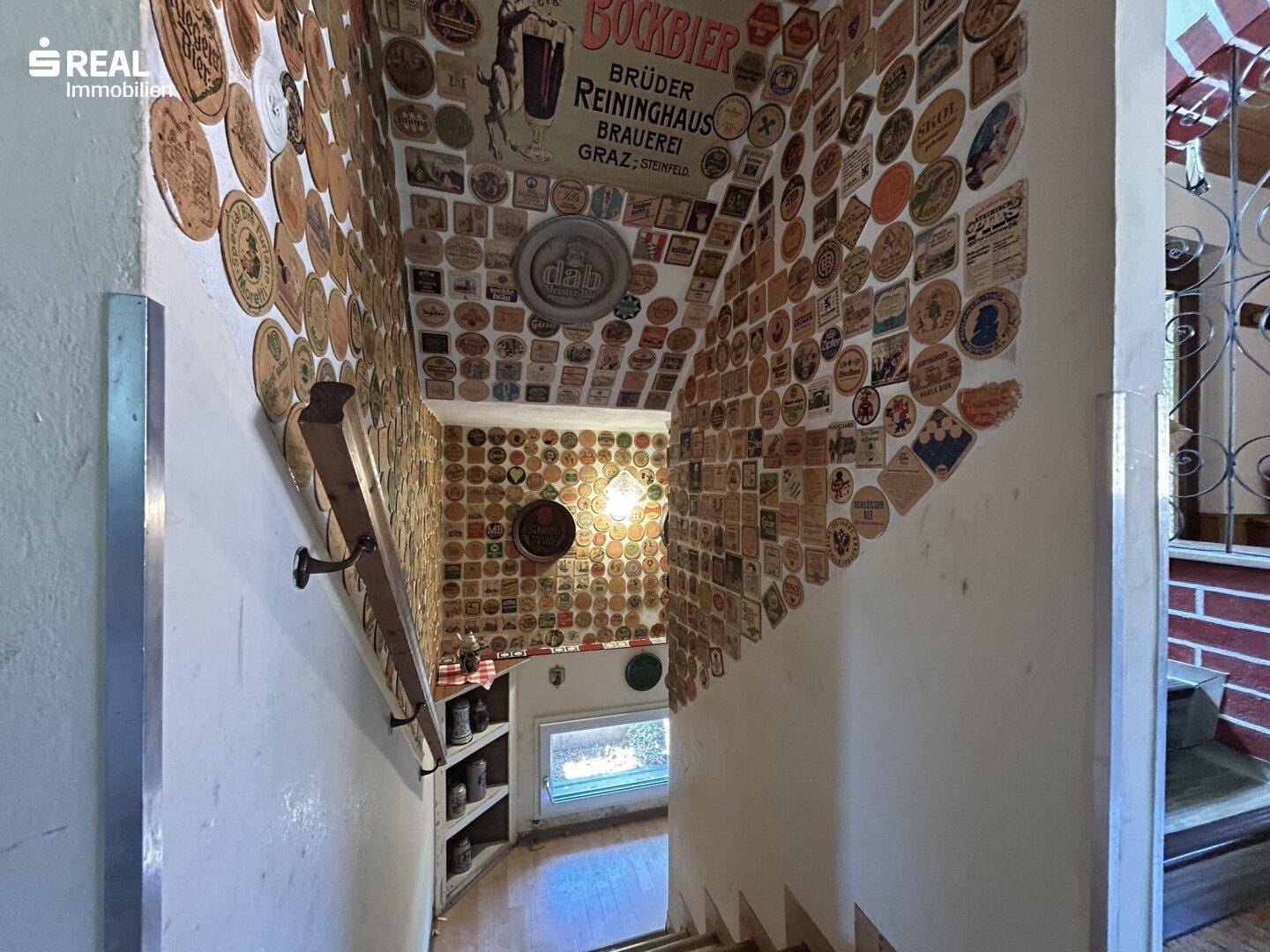 Treppenhaus mit einzigartiger Dekoration aus Bierdeckeln an Wänden und Decke.