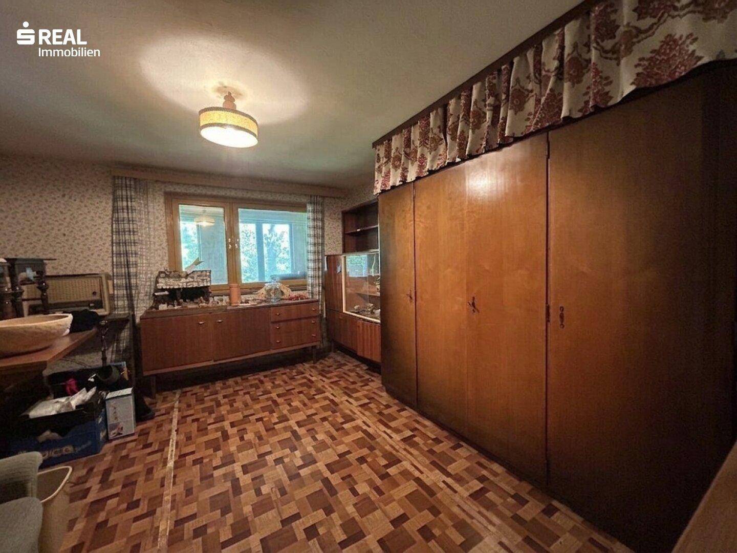 Raum mit gemustertem Bodenbelag und großen, traditionellen Holzschränken.