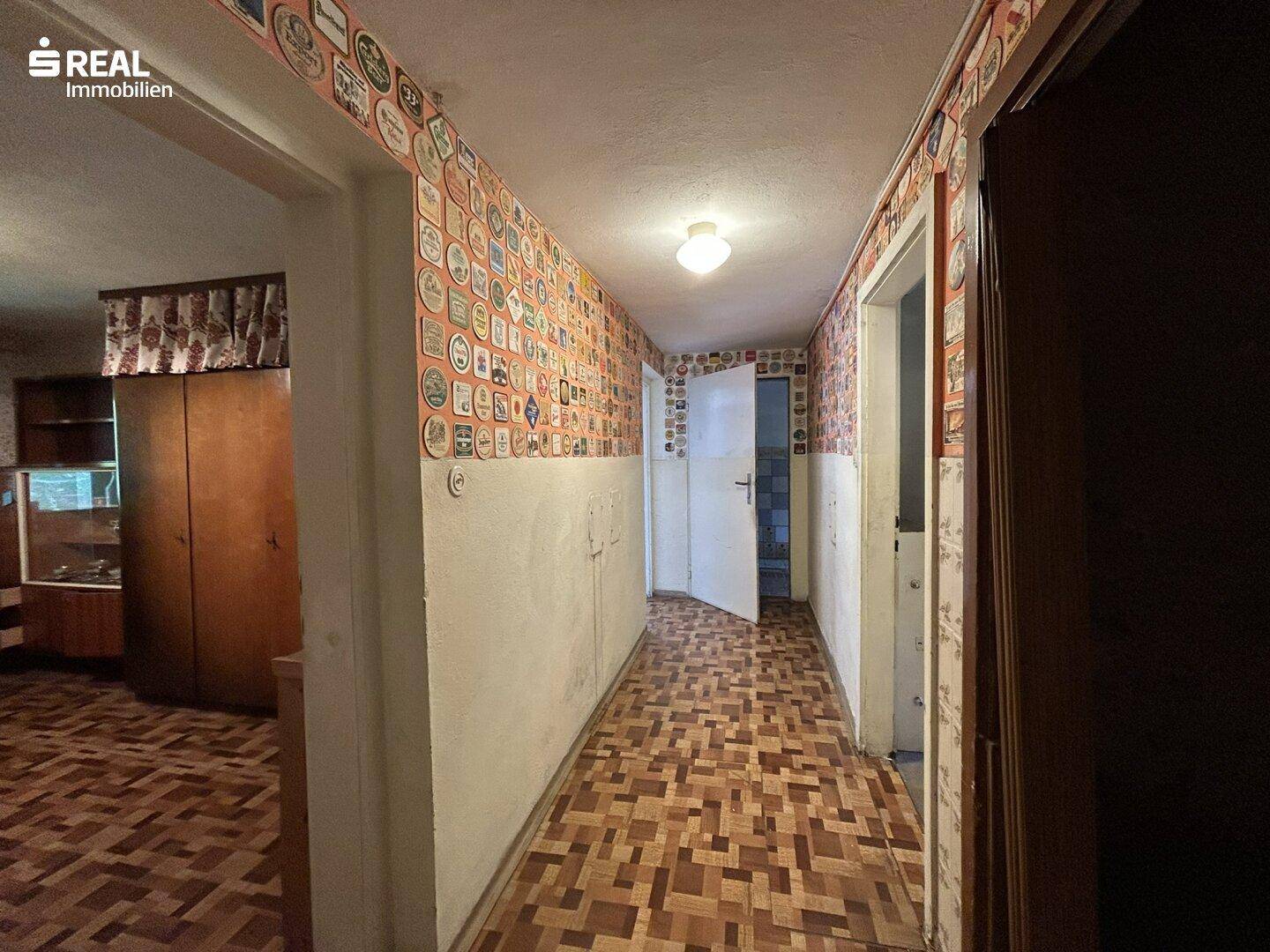 Langer Flur mit gemustertem Boden und dekorativen Elementen an den Wänden.