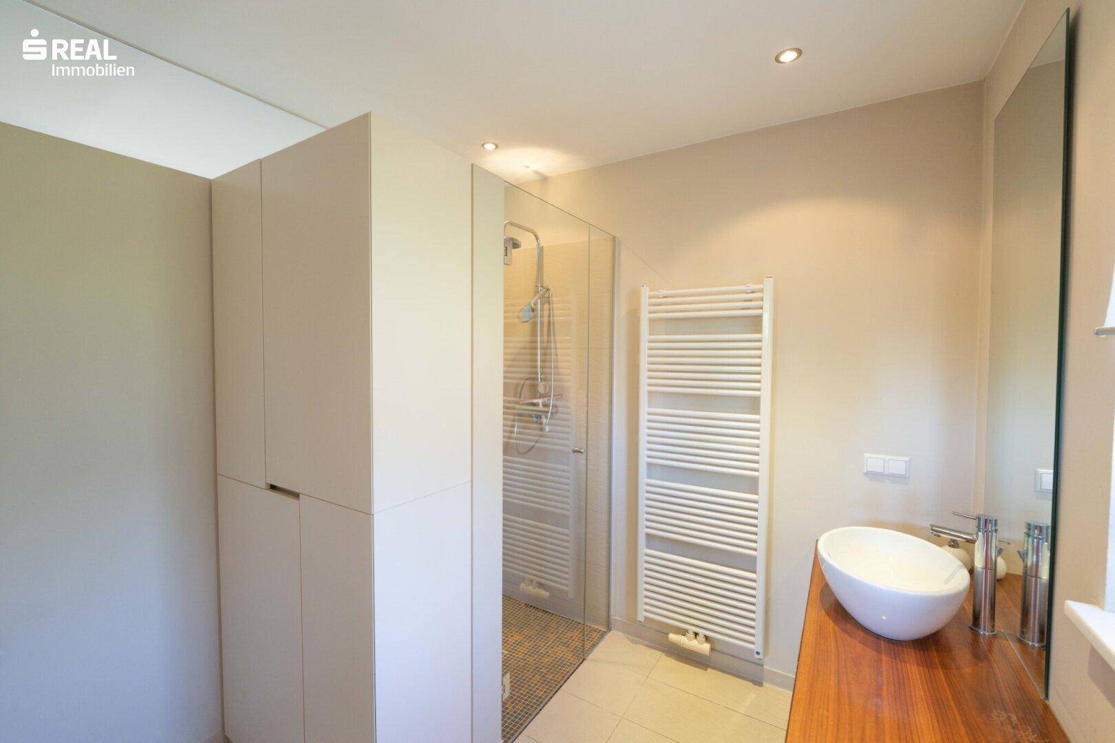 Modernes Badezimmer mit begehbarer Dusche, Einzelwaschbecken und beheiztem Handtuchhalter.
