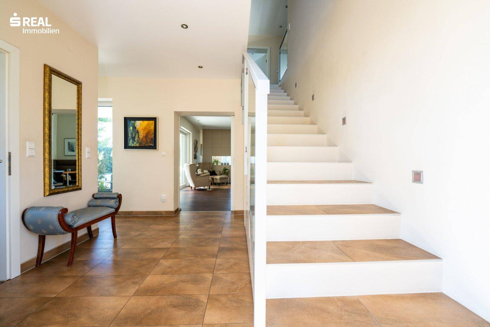 Geräumiger Flur mit Treppe, Fliesenboden und Blick in den Wohnbereich.