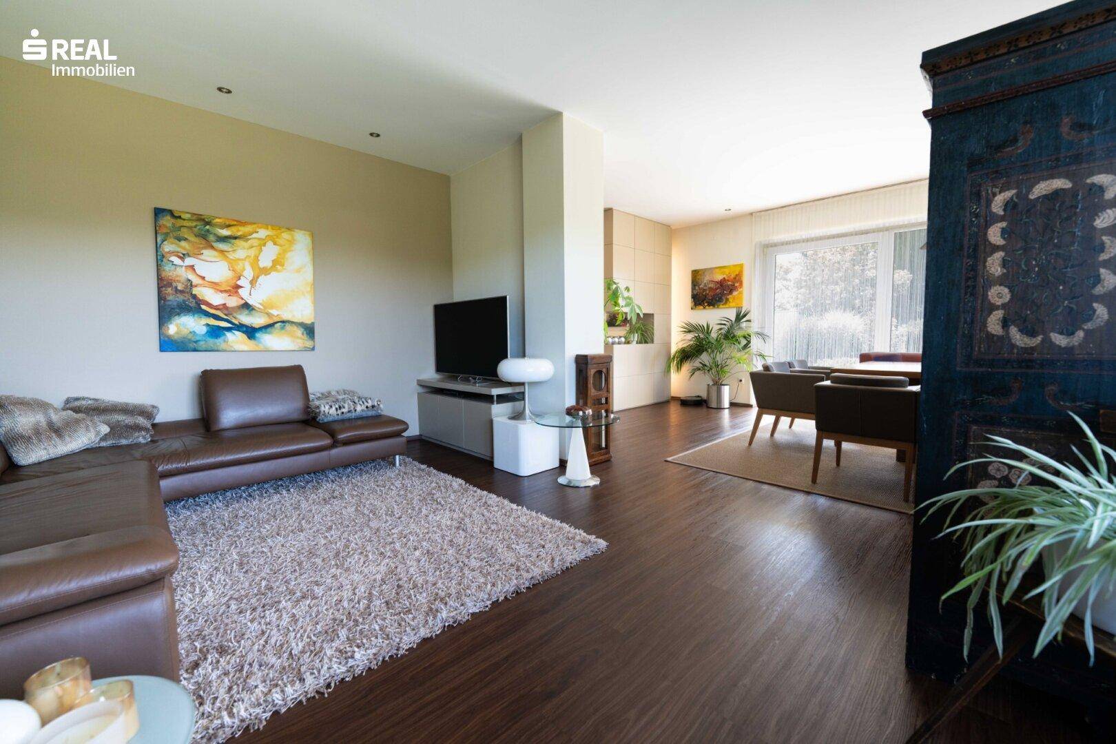 Gemütlicher Wohnbereich mit Ledersofa, Teppich und moderner Kunst an der Wand.