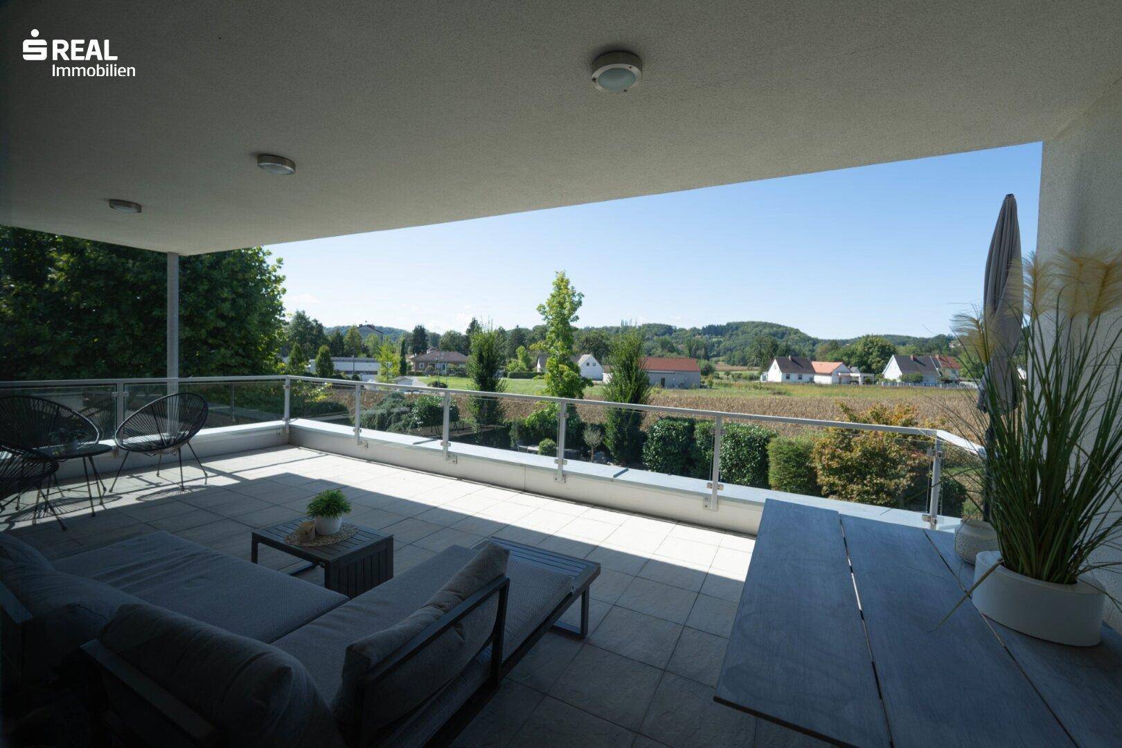Großer Balkon mit Sitzgelegenheiten, Fliesenboden und weitem Blick über die Landschaft.