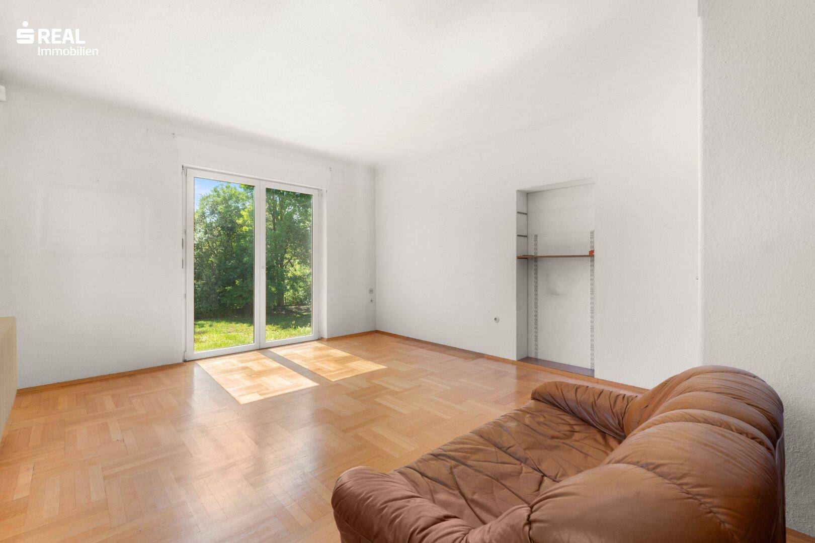 Helles Wohnzimmer mit Parkettboden und großer Schiebetür zum Gartenbereich.