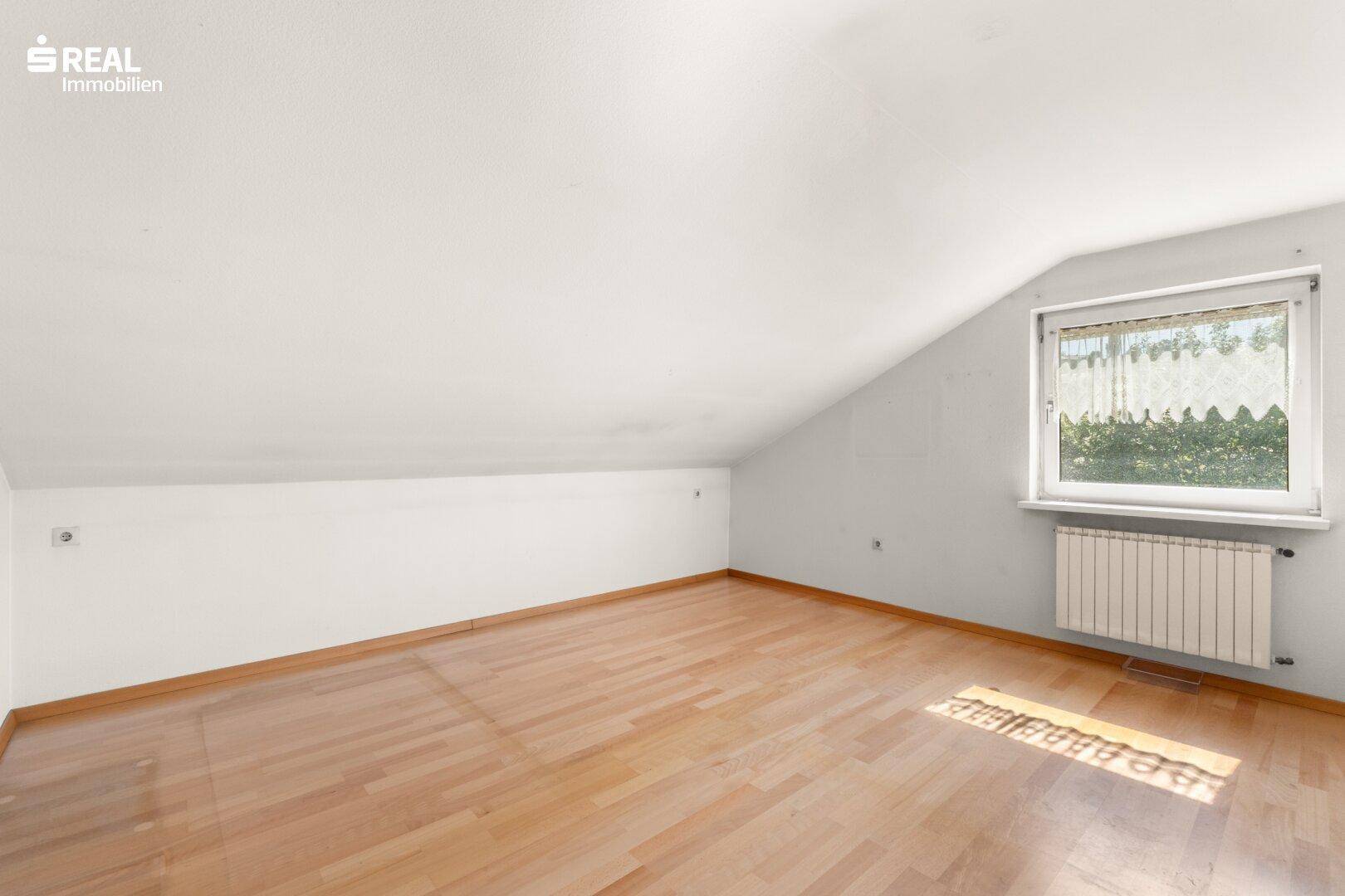 Helles Dachgeschosszimmer mit Schrägen und Laminatboden, ideal als Kinderzimmer.
