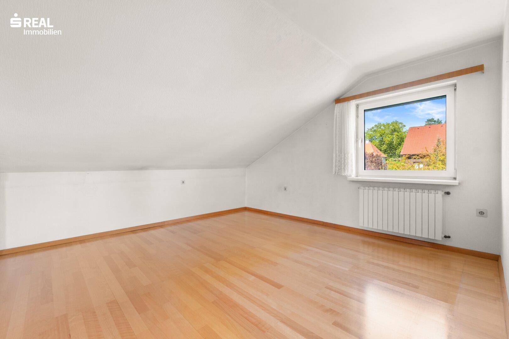Geräumiges Dachgeschosszimmer mit Schrägen und hellem Laminatboden.