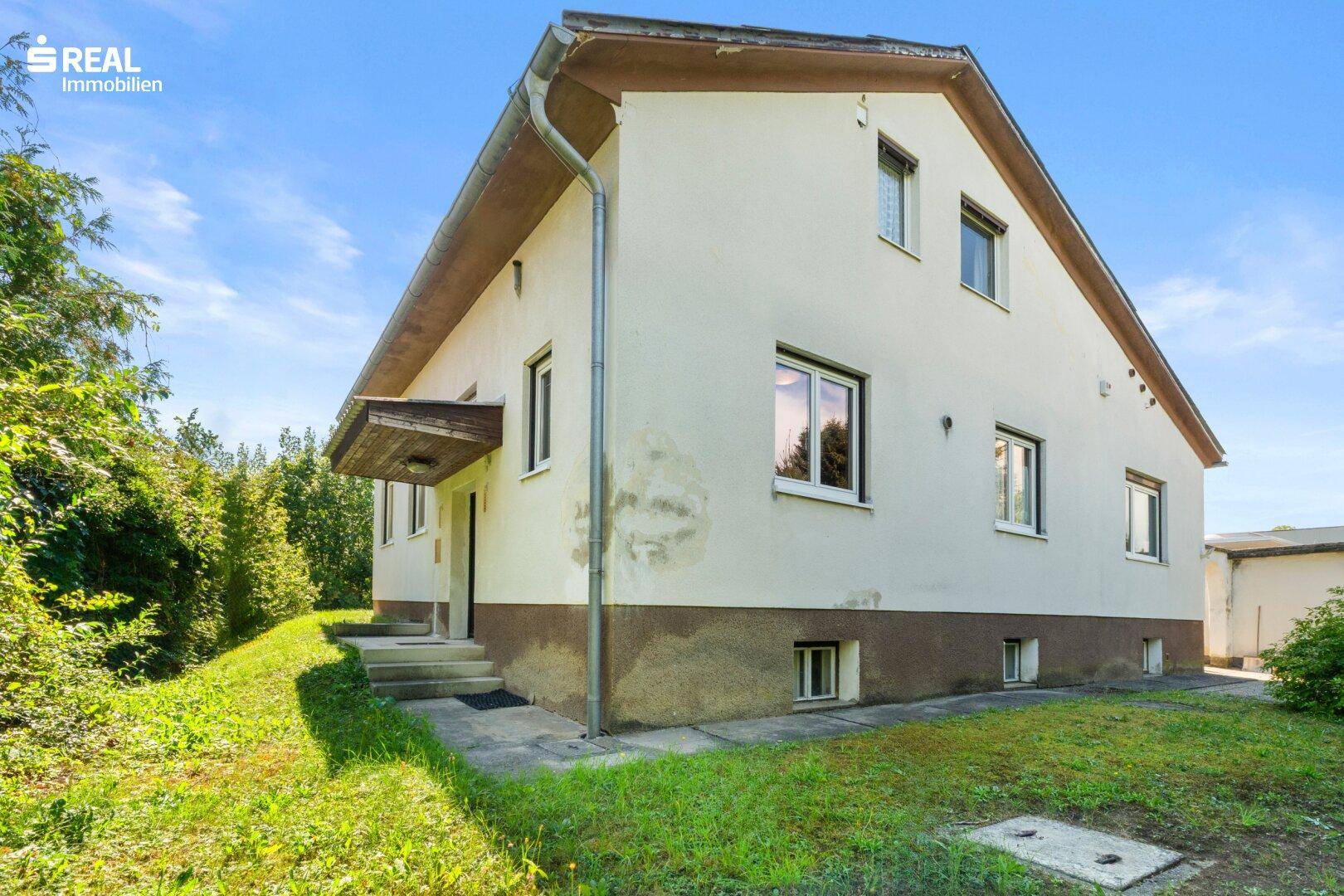 Seitenansicht des Hauses mit Eingangsbereich und gepflegter Grünfläche.