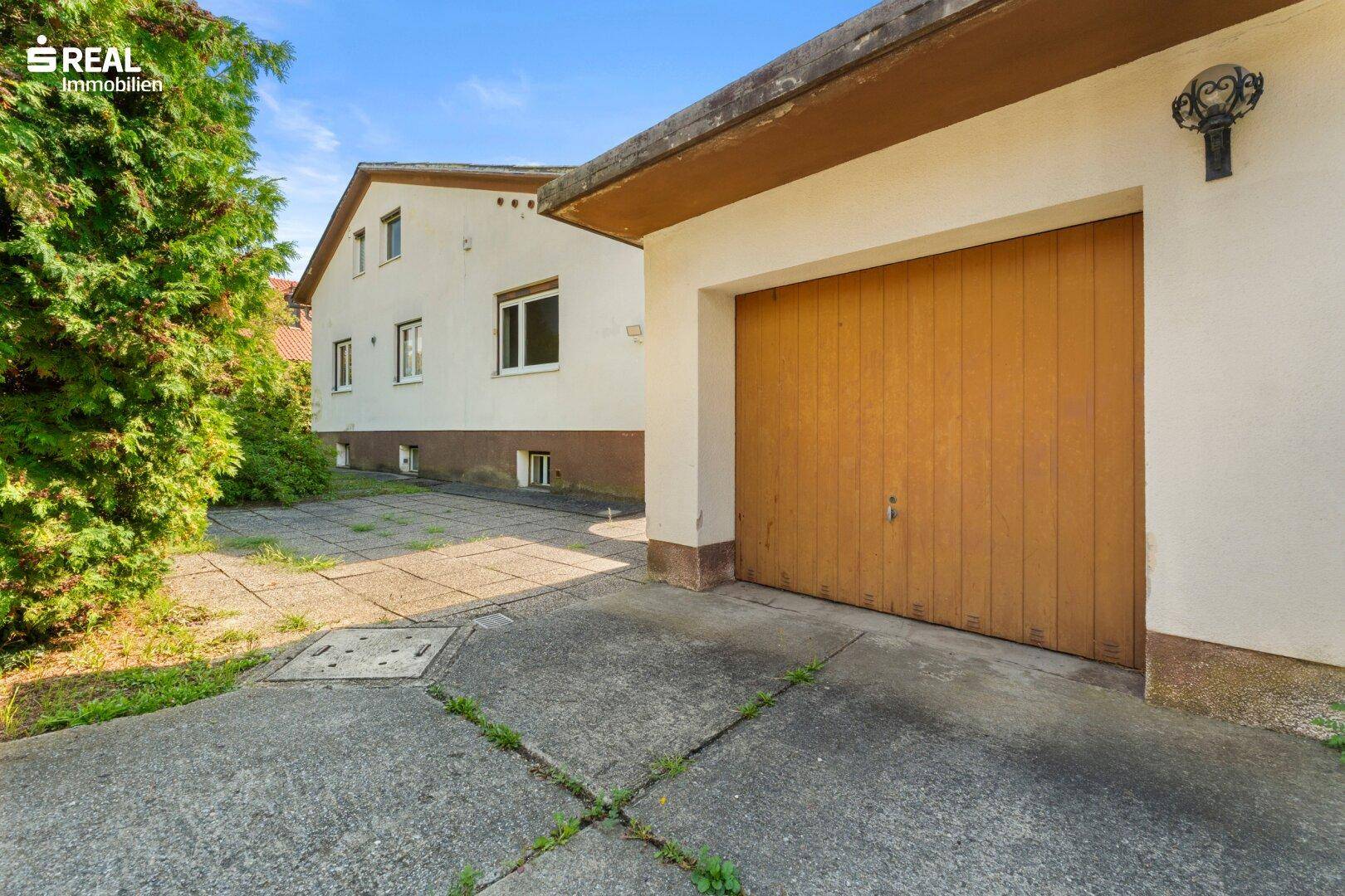 Einzelgarage mit Holztor und Zufahrt, angrenzend an das Wohnhaus.