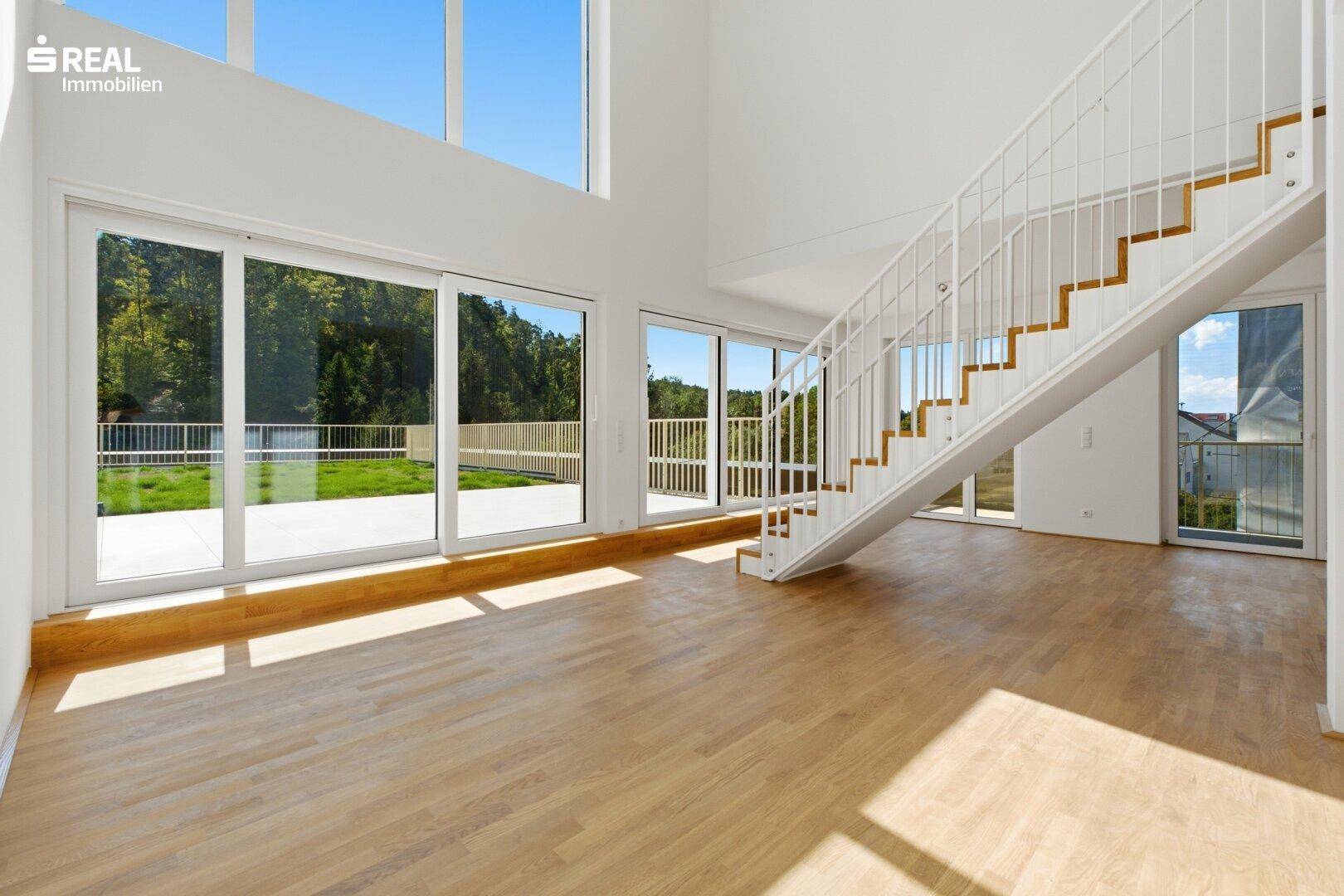 Helles Wohnzimmer mit hohen Decken, Holzfußboden und moderner Treppe.