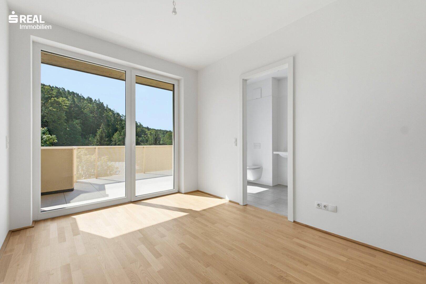 Leeres Zimmer mit Parkettboden und angrenzendem Badezimmer, ideal als Schlafzimmer.