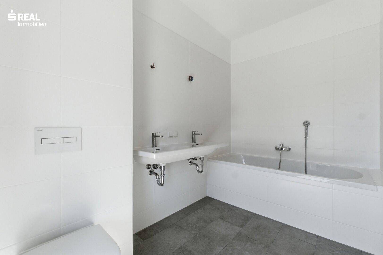 Modernes Badezimmer mit Doppelwaschbecken, Badewanne und weißen Fliesen.
