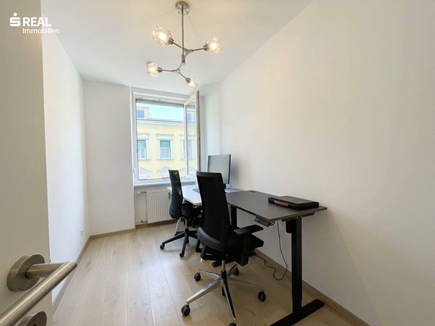 Helles Arbeitszimmer mit zwei Schreibtischen, Bürostühlen und Blick aus dem Fenster.