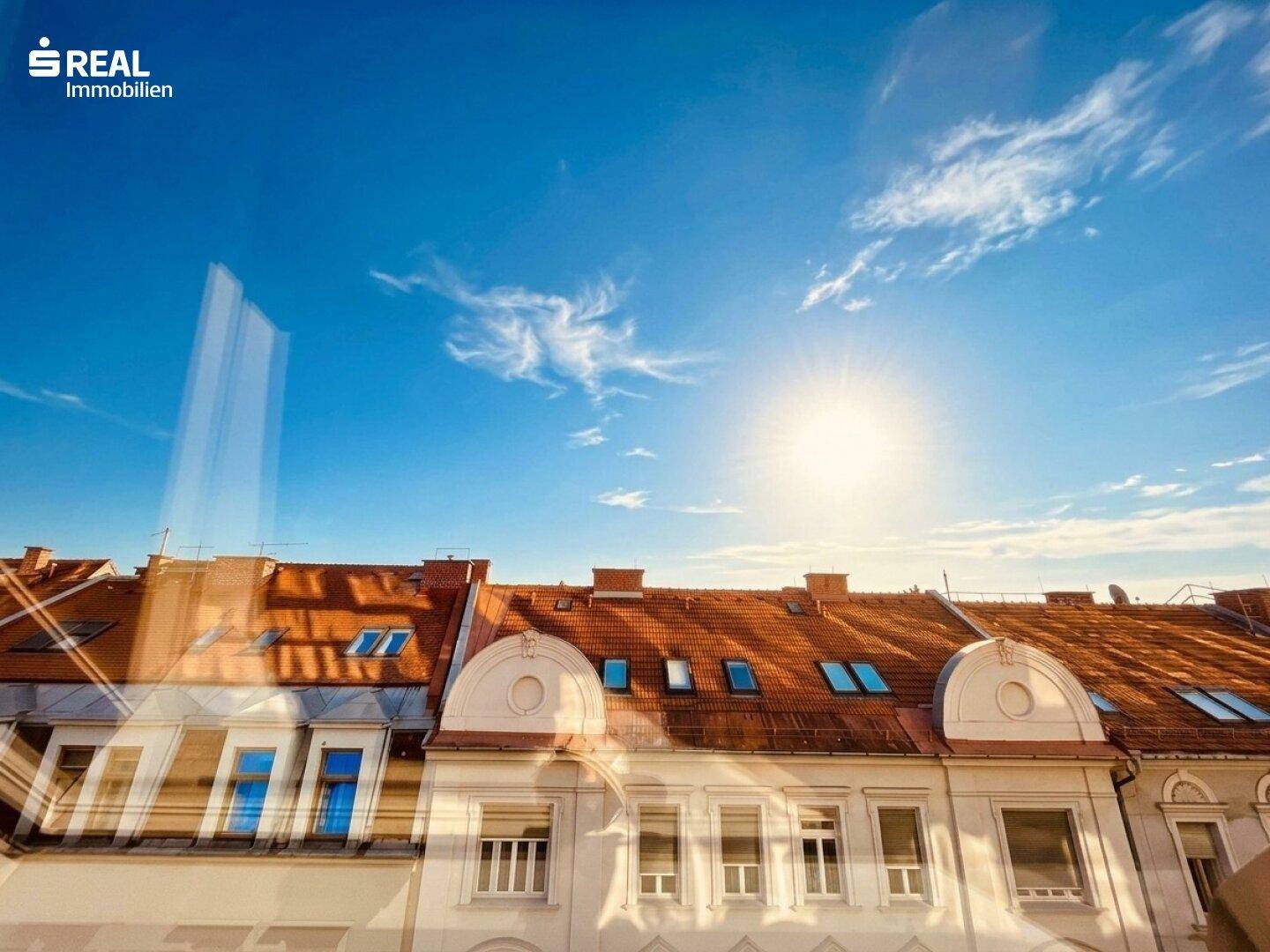 Sonniger Blick über die Dächer der Stadt mit blauem Himmel und historischen Gebäuden.