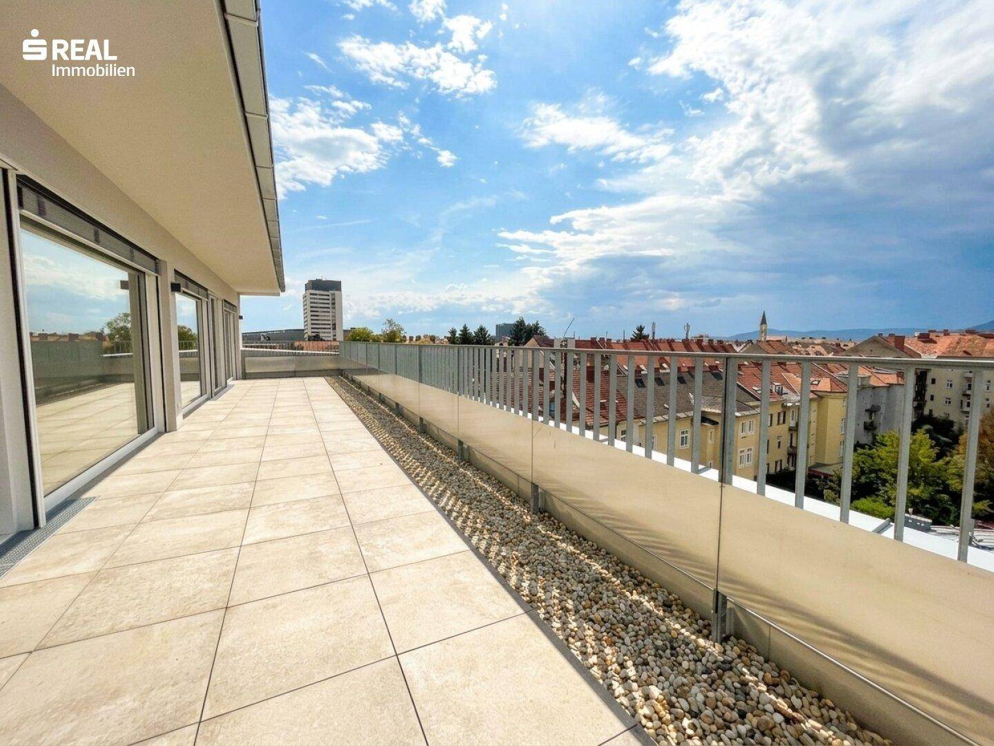 Geräumige Dachterrasse mit Fliesenboden und weitem Panoramablick über die Dächer der Stadt.