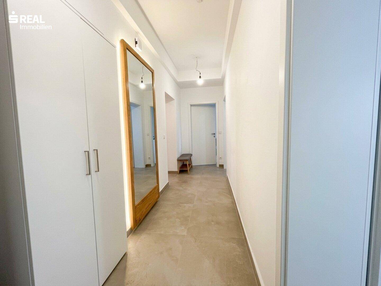 Geräumiger Flur mit großem Spiegel, Einbauschrank und hellem Fliesenboden.