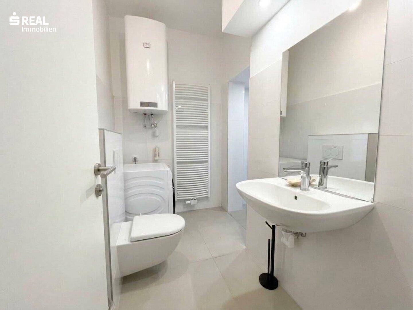 Modernes Badezimmer mit wandhängendem WC, Waschbecken und beheiztem Handtuchhalter.
