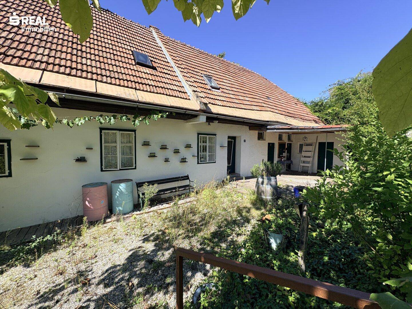 Seitenansicht des Hauses mit kleinem Gartenbereich, Sitzbank und traditionellen Fenstern.