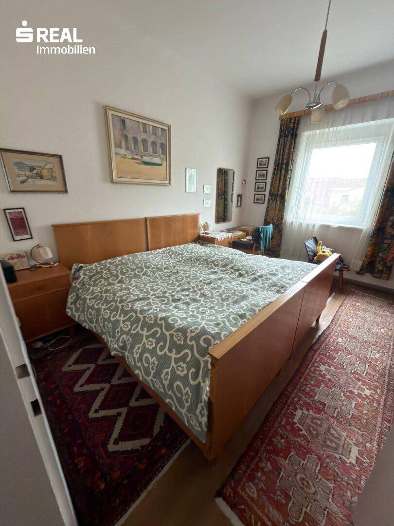Geräumiges Schlafzimmer mit großem Doppelbett, Teppich und Fenster, hell und freundlich.