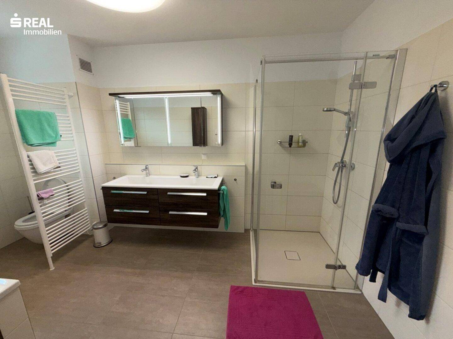 Modernes Badezimmer mit Doppelwaschbebecken, großer Duschkabine und beheiztem Handtuchhalter.