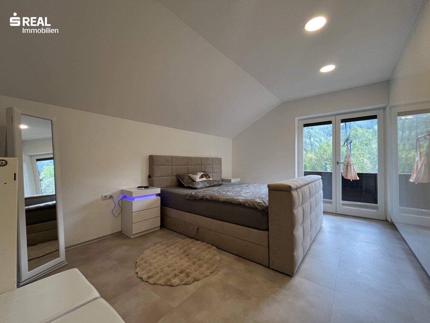 Gemütliches Schlafzimmer im Dachgeschoss mit Schrägdach, Balkonzugang und Blick ins Grüne.