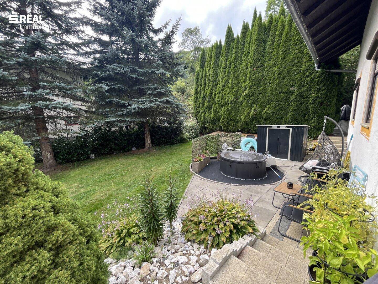 Idyllischer Gartenbereich mit Whirlpool, Sitzgelegenheiten und üppiger Bepflanzung für Entspannung.