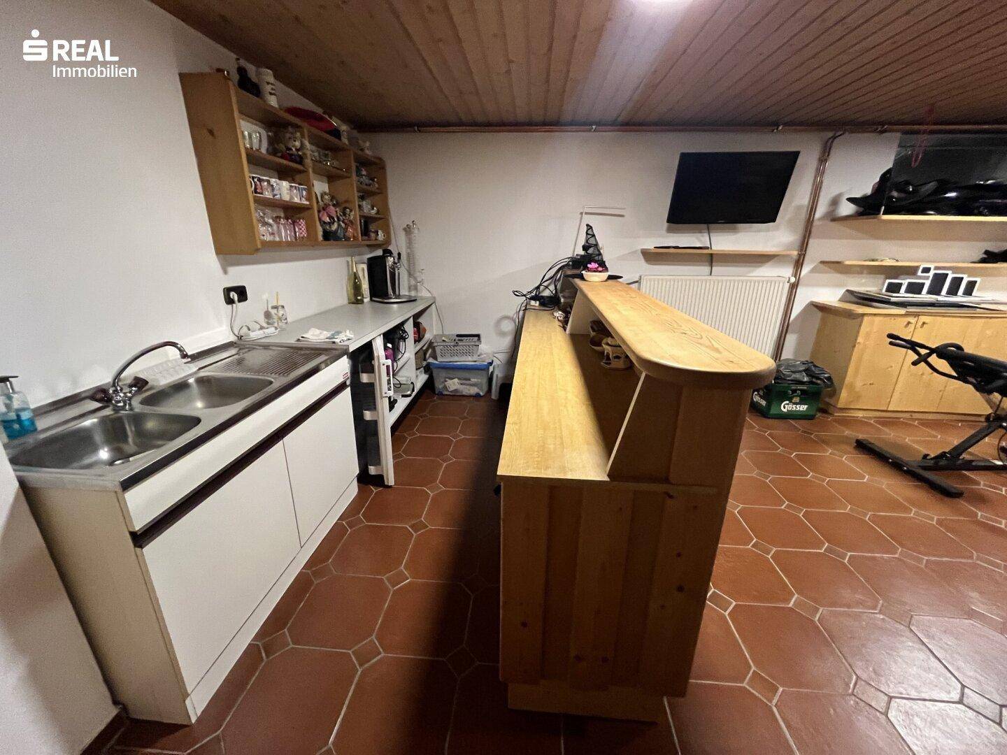 Kellerraum mit kleiner Küchenzeile, Spülbecken und einer Bar für gesellige Abende.