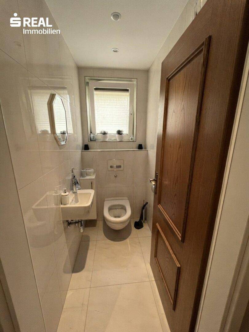 Kleines, modernes Gäste-WC mit Fenster, Wand-WC und kompaktem Waschbecken.