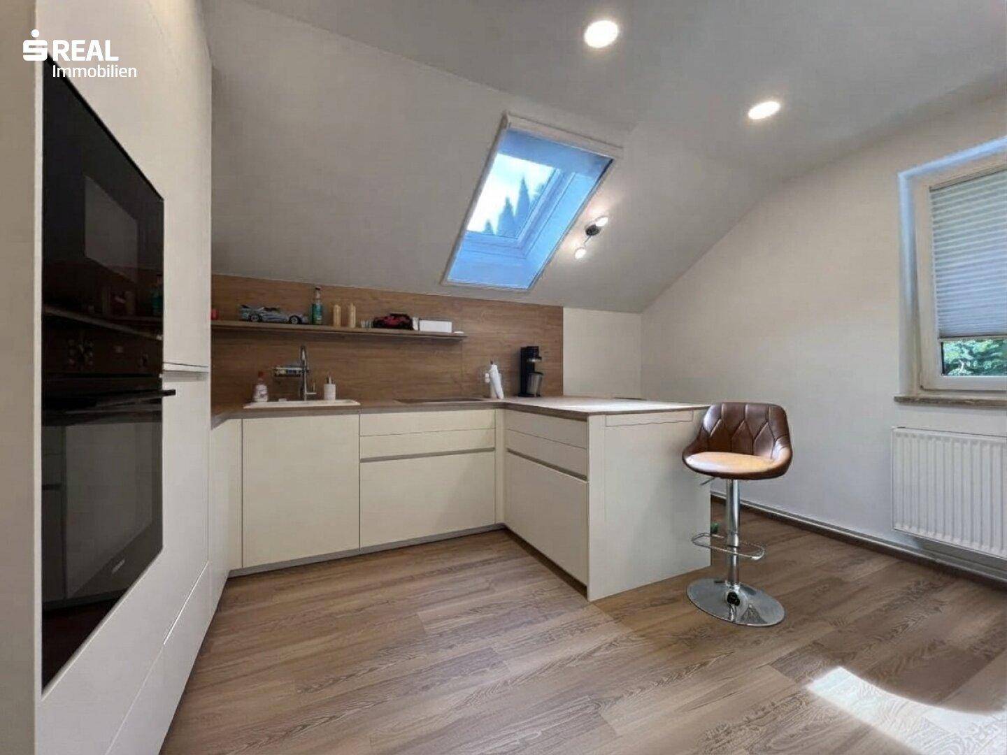 Helle Dachgeschossküche mit Schrägdach, Dachfenster und moderner Ausstattung.