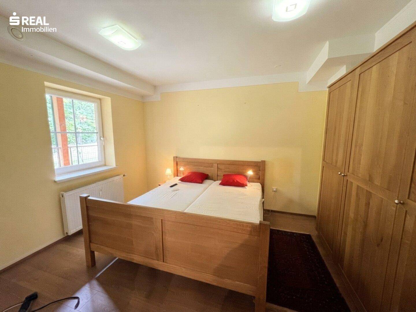 Gemütliches Schlafzimmer mit Doppelbett, Holzschrank und gelben Wänden.