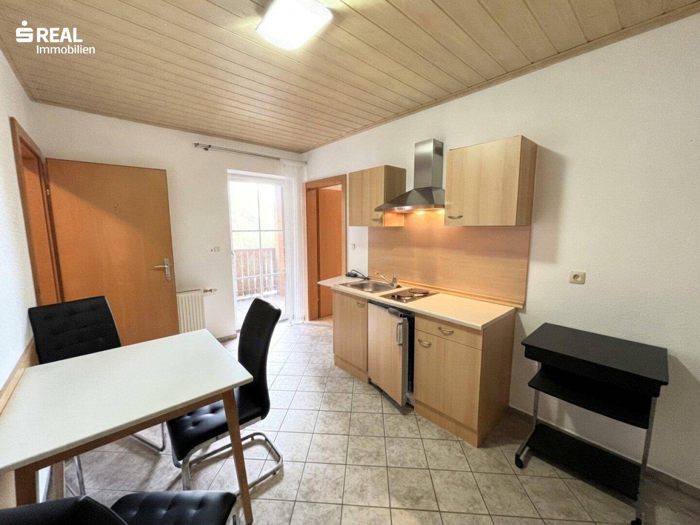 Kleine, funktionale Küchenzeile mit Essbereich und Zugang zu einem Balkon.