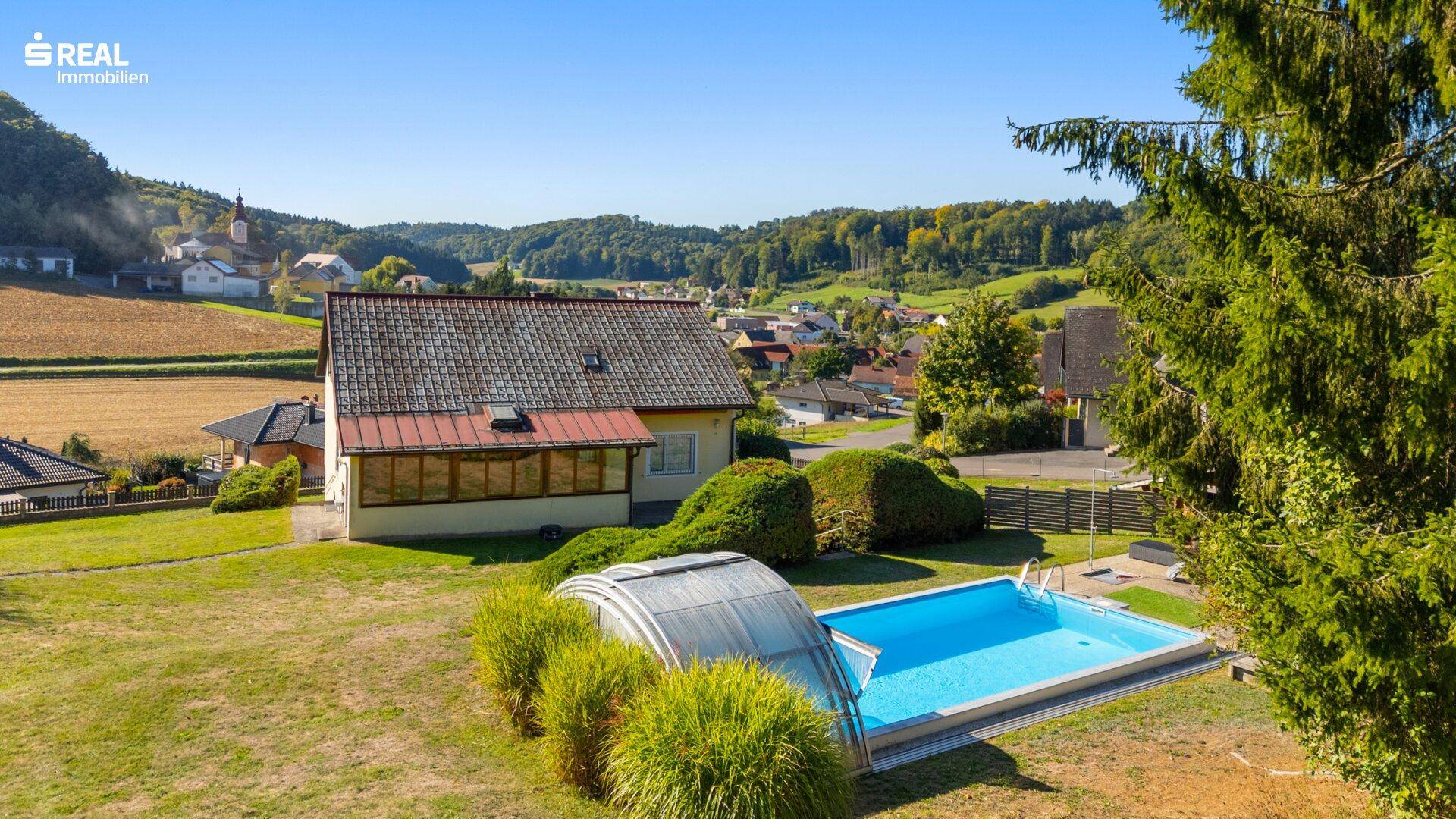 Rückansicht des Hauses mit Swimmingpool und umgebender ländlicher Landschaft.