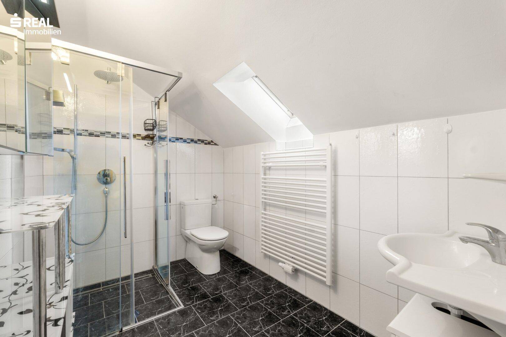 Modernes Badezimmer mit Dusche, Dachfenster und beheiztem Handtuchhalter in Weiß.