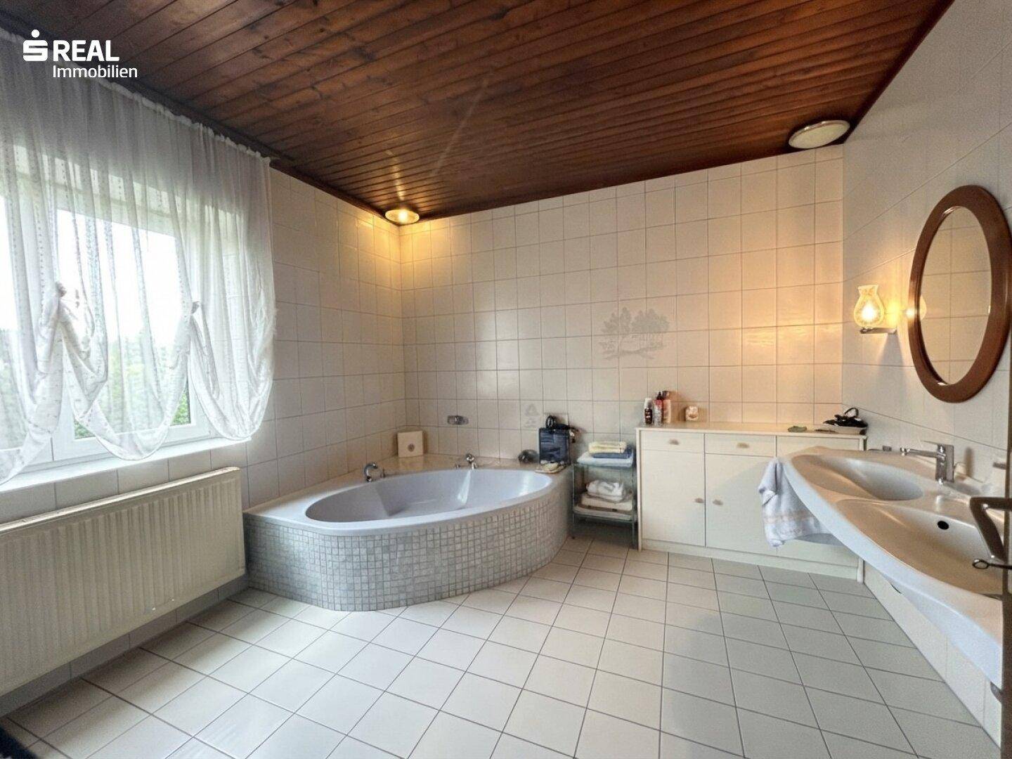 Geräumiges Badezimmer mit Eckbadewanne, Doppelwaschbecken und Holzdecke.