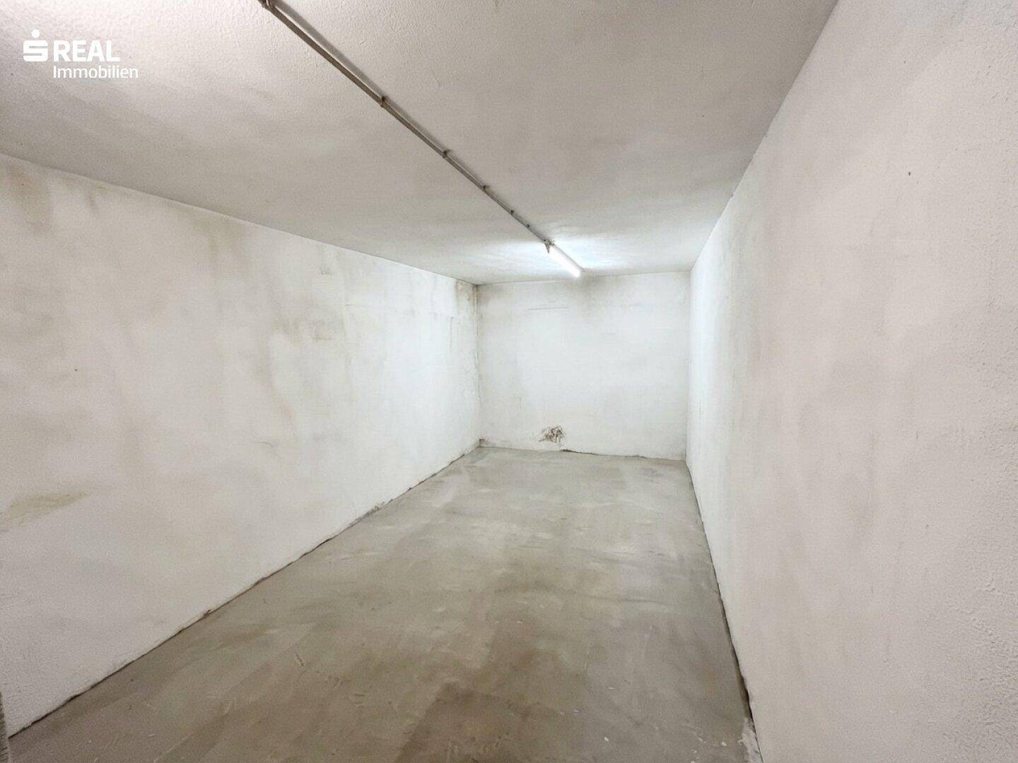Leerer Kellerraum mit Betonboden und weiß gestrichenen Wänden.