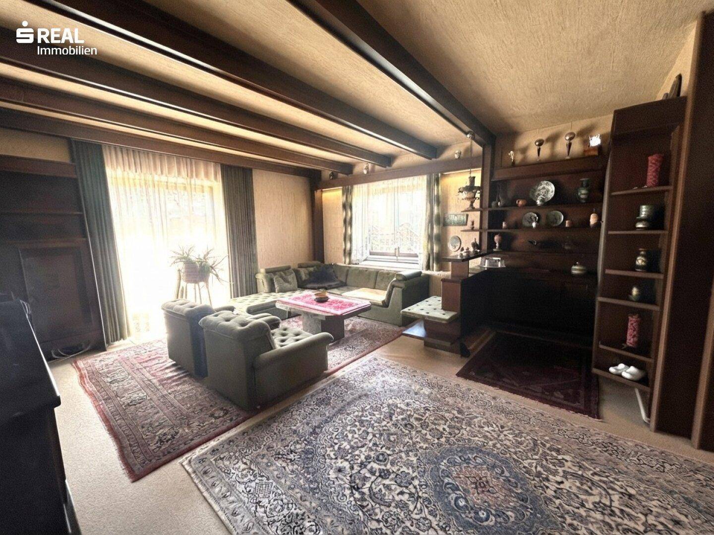 Großes Wohnzimmer mit Holzbalkendecke, Teppichen und traditionellen Möbeln.