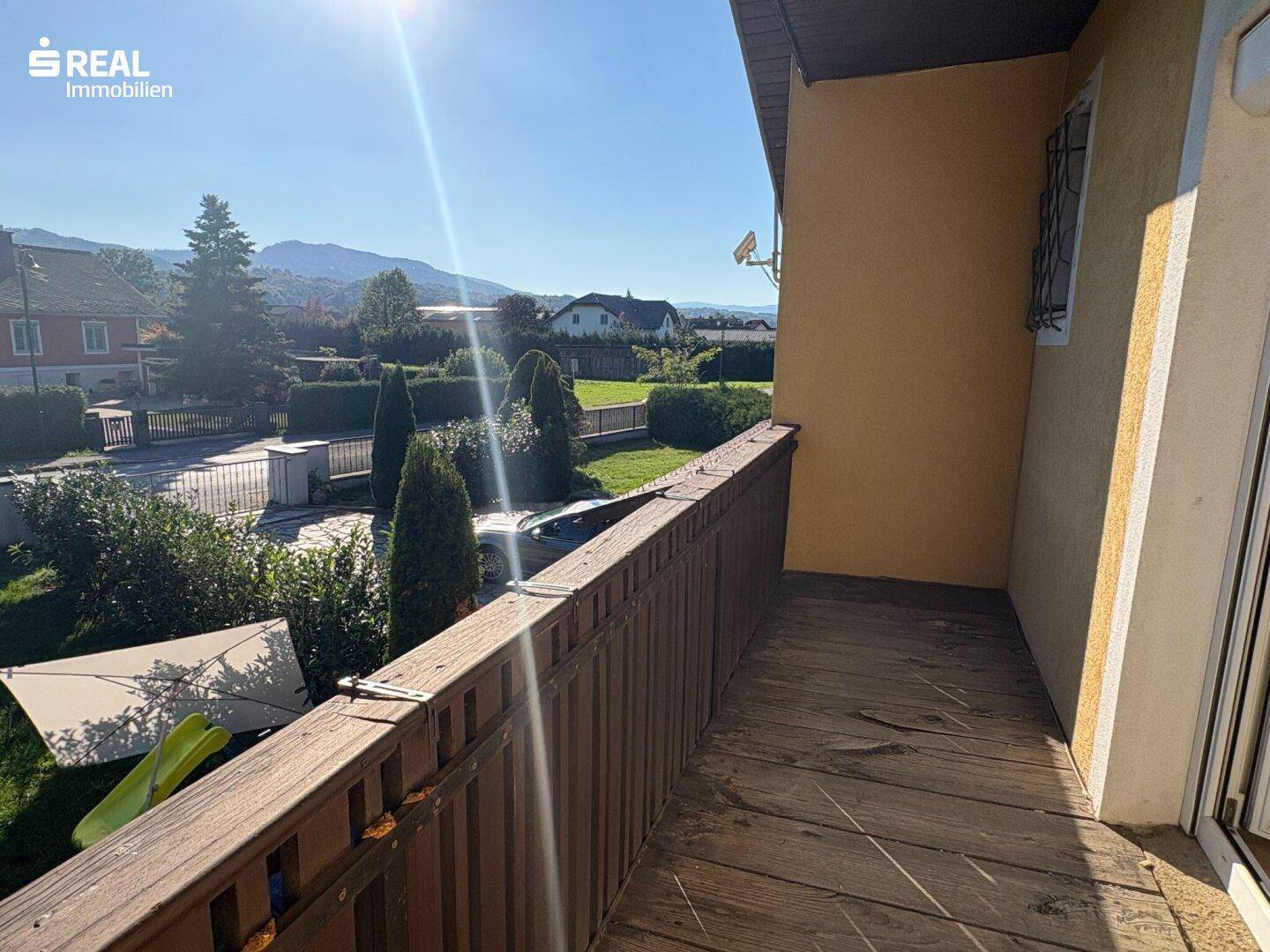 Holzbalkon mit traditionellem Geländer bietet einen weiten Blick auf die grüne Umgebung.