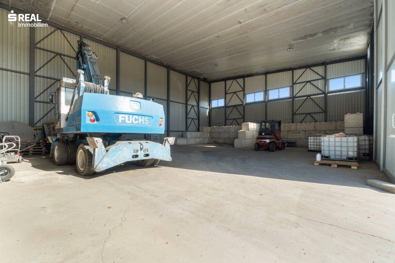 Geräumige Lagerhalle mit Betonboden, hohen Decken und einem großen Tor zur Außenseite.