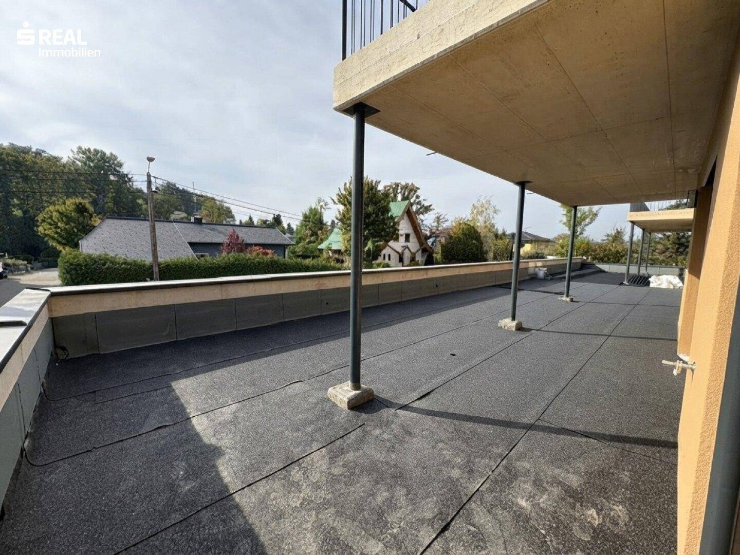 Weitläufige Terrasse im Erdgeschoss eines Neubaus mit Blick auf die umliegende Wohngegend.