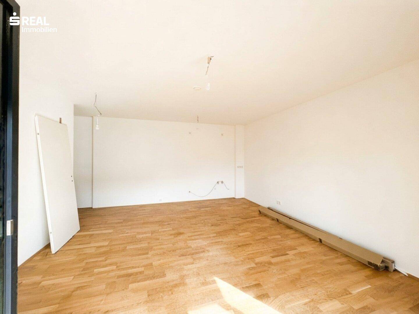 Geräumiges, unmöbliertes Zimmer mit Parkettboden und viel Tageslicht, bereit für die Einrichtung.